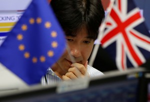 An employees of a foreign exchange trading company works as he is seen between British Union flag and an EU flag in Tokyo